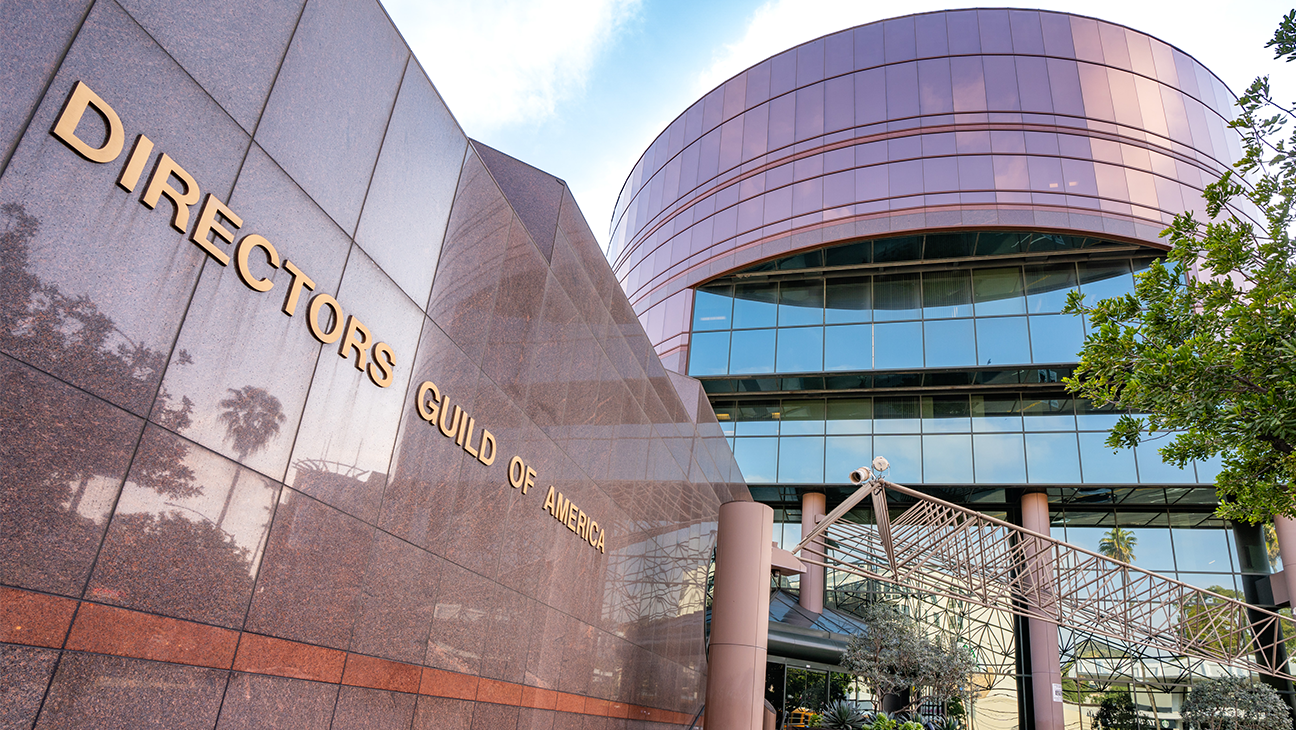 Exterior of the Directors Guild of America building with a curved glass facade and a bronze sign reading 'Directors Guild of America'