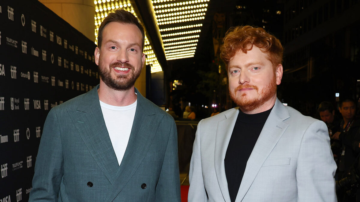 Two men in suits posing for cameras on a TIFF red carpet at night.