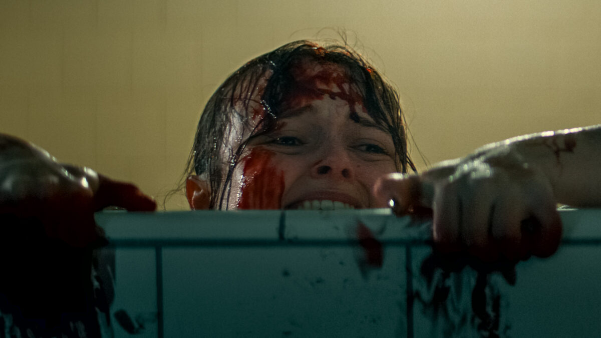 Child in a bathtub, blood on face and hands, looking distressed.