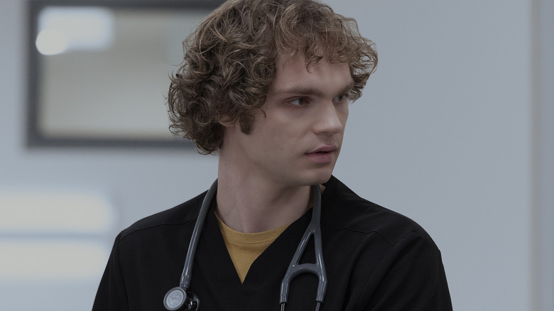 James Ogilvie in a black shirt and a stethoscope around his neck looking to his left in The Pitt Season 2