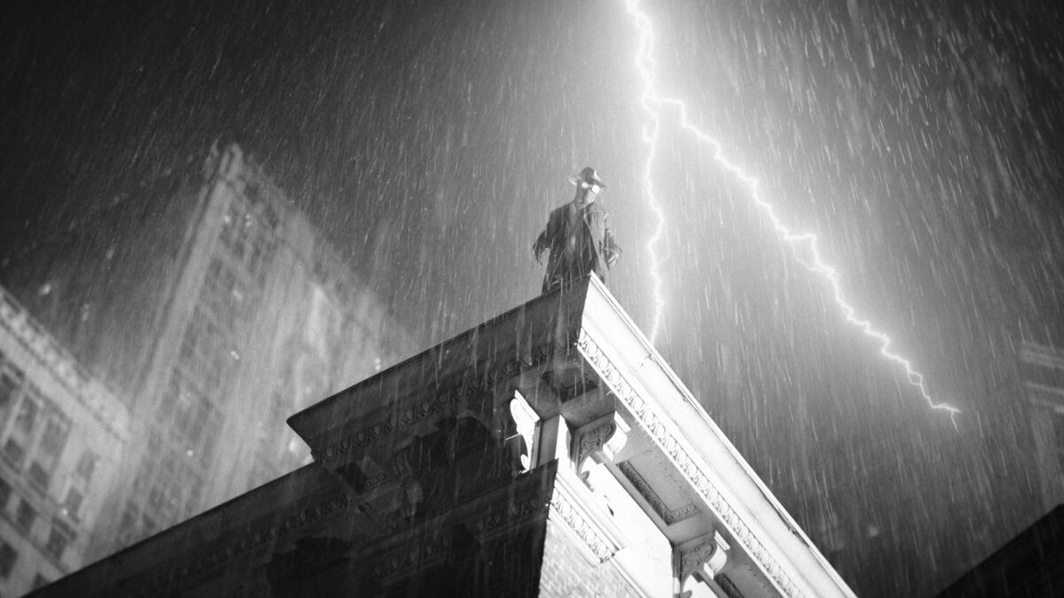 Statue atop a classical building caught in a thunderstorm, with a bright lightning bolt striking the sky behind it.