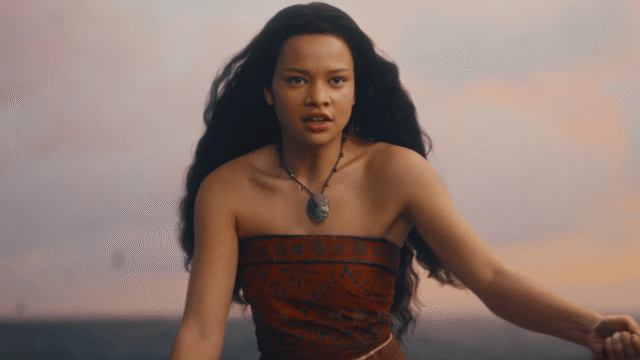 Woman with long dark hair in a strapless orange dress and turquoise pendant necklace at the beach at sunset.