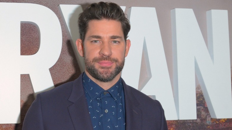 John Krasinski in front of a Jack Ryan poster