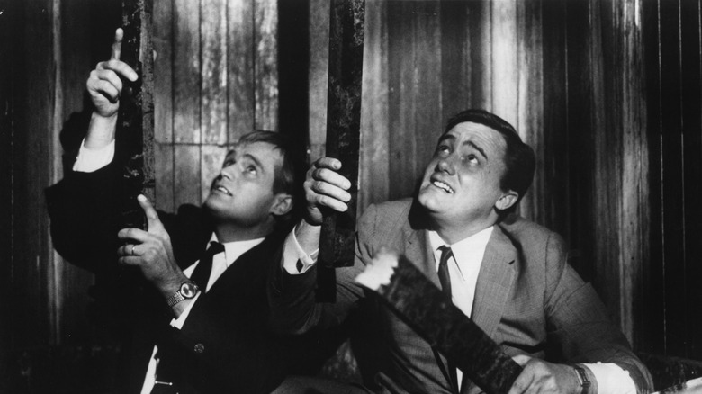 Illya Kuryakin pointing up and Napoleon Solo holding a broken board