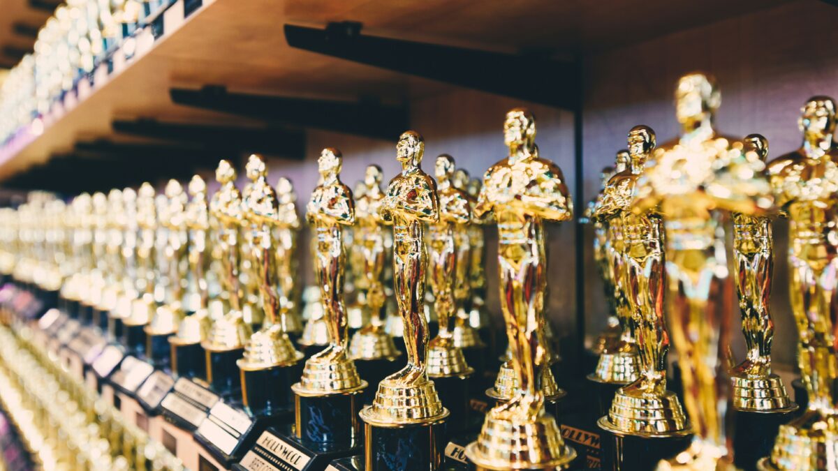 Rows of shiny gold statuette trophies on display in a store aisle.