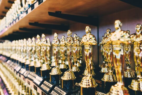 Rows of shiny gold statuette trophies on display in a store aisle.