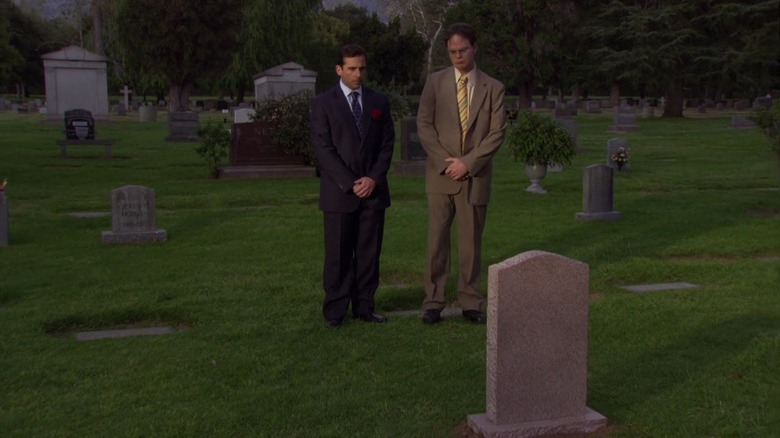Michael and Dwight stand respectfully before a grave in The Office.