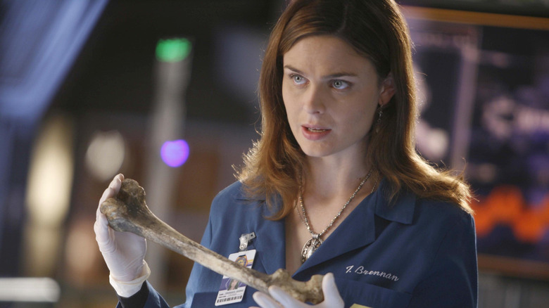 Emily Deschanel as Dr. Temperance Brennan holding a bone in a forensic lab in a scene from the series "Bones."