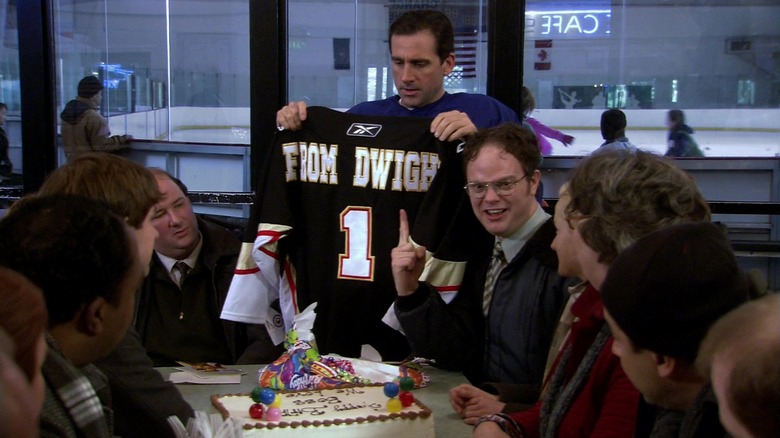 Michael holds up a hockey jersey from Dwight in front of his employees in The Office.