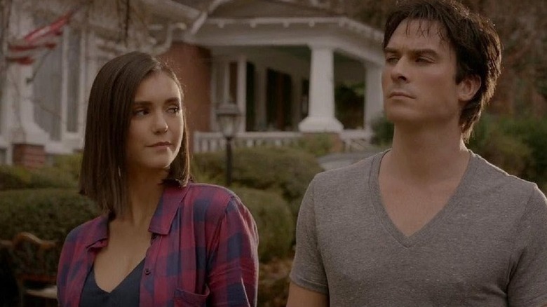 Elena and Damon walk down the street and look at each other in The Vampire Diaries