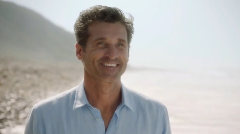 Patrick Dempsey as Derek Shepherd stands next to a beach on Grey's Anatomy