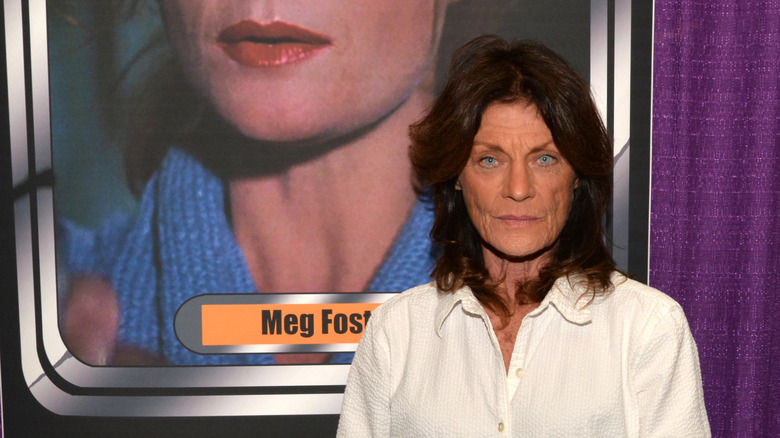 Meg Foster at a horror convention in front of a still of her performance in "They Live."