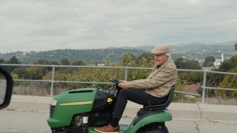Bill riding a lawnmower on the road