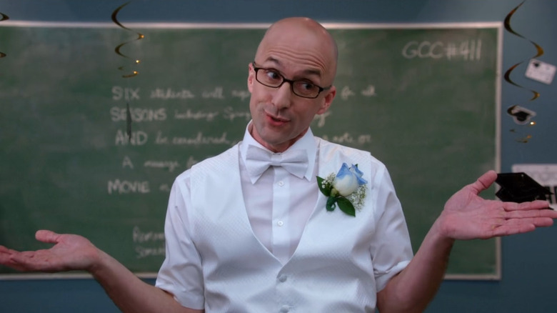 Dean Pelton stands in front of a chalkboard reading "six seasons and a movie" in "Community" (2009)