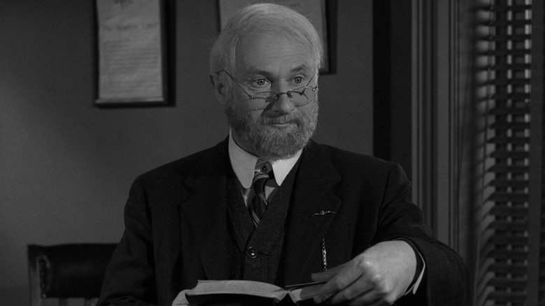 Ellis holding a book and looking on