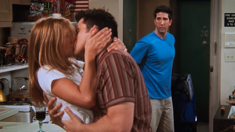 Jennifer Aniston as Rachel Green kissing Matt LeBlanc as Joey Tribbiani while David Schwimmer as Ross Geller walks in on them in Friends