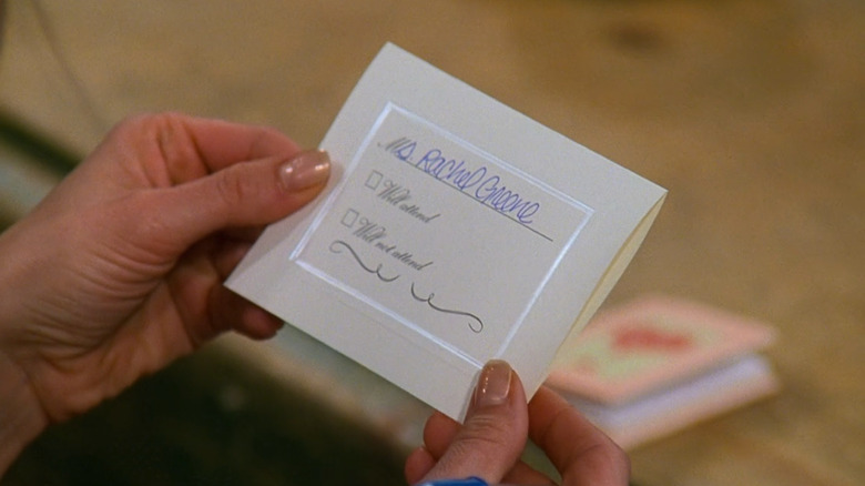 Close up on Jennifer Aniston as Rachel Green or Greene's hand holding an invitation to Ross and Emily's wedding in Friends