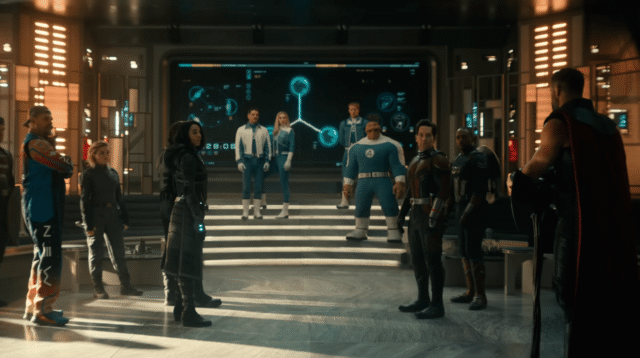 Several costumed figures stand in a futuristic room with glowing wall displays and steps.