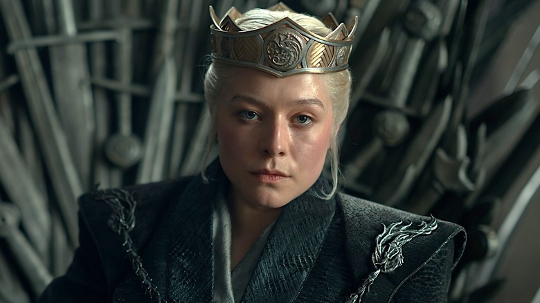 Closeup of Rhaenyra sitting on the Iron Throne with a crown on her head in House of the Dragon