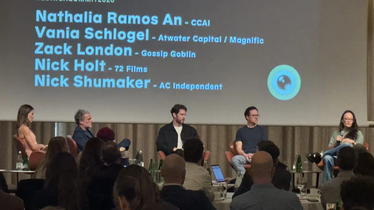 Five people sit onstage before an audience beneath a projection listing #ZURICHSUMMIT2026 and names.