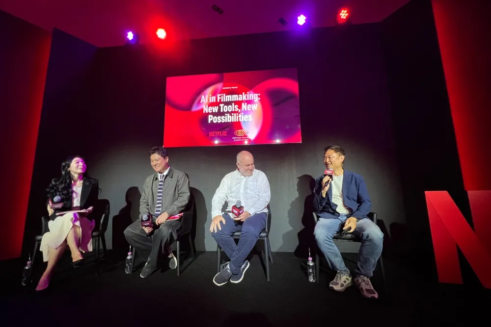 Four people sit on a stage with microphones beneath a screen reading “AI in Filmmaking: New Tools, New Possibilities.”