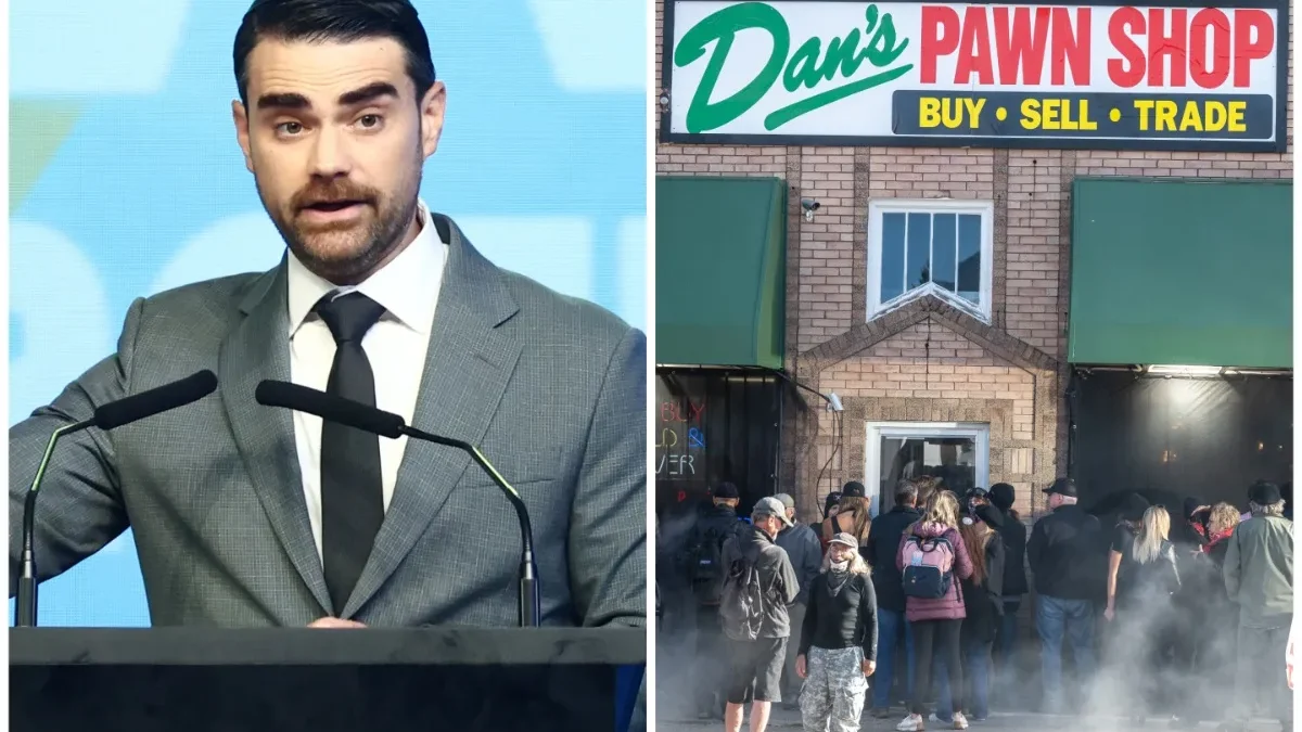 A suited man speaks at microphones beside a crowd outside Dan’s Pawn Shop with smoke nearby.