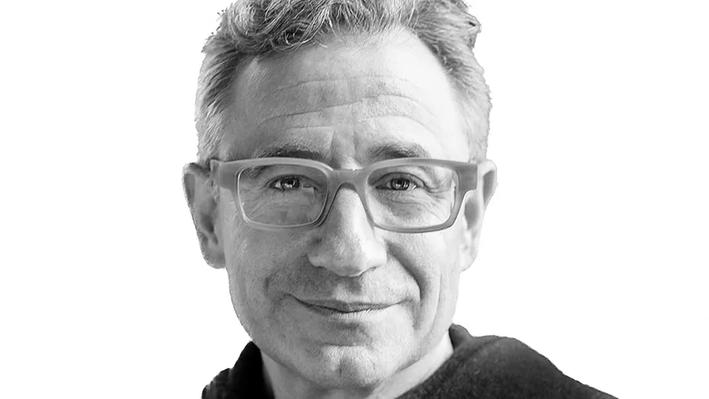 Black-and-white close-up portrait of a man wearing glasses and smiling slightly.