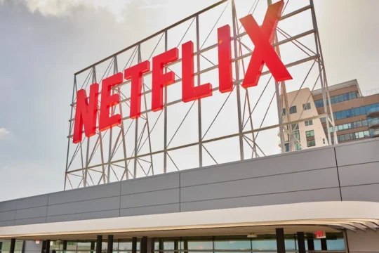 Large red Netflix sign mounted on a metal frame above a building exterior.
