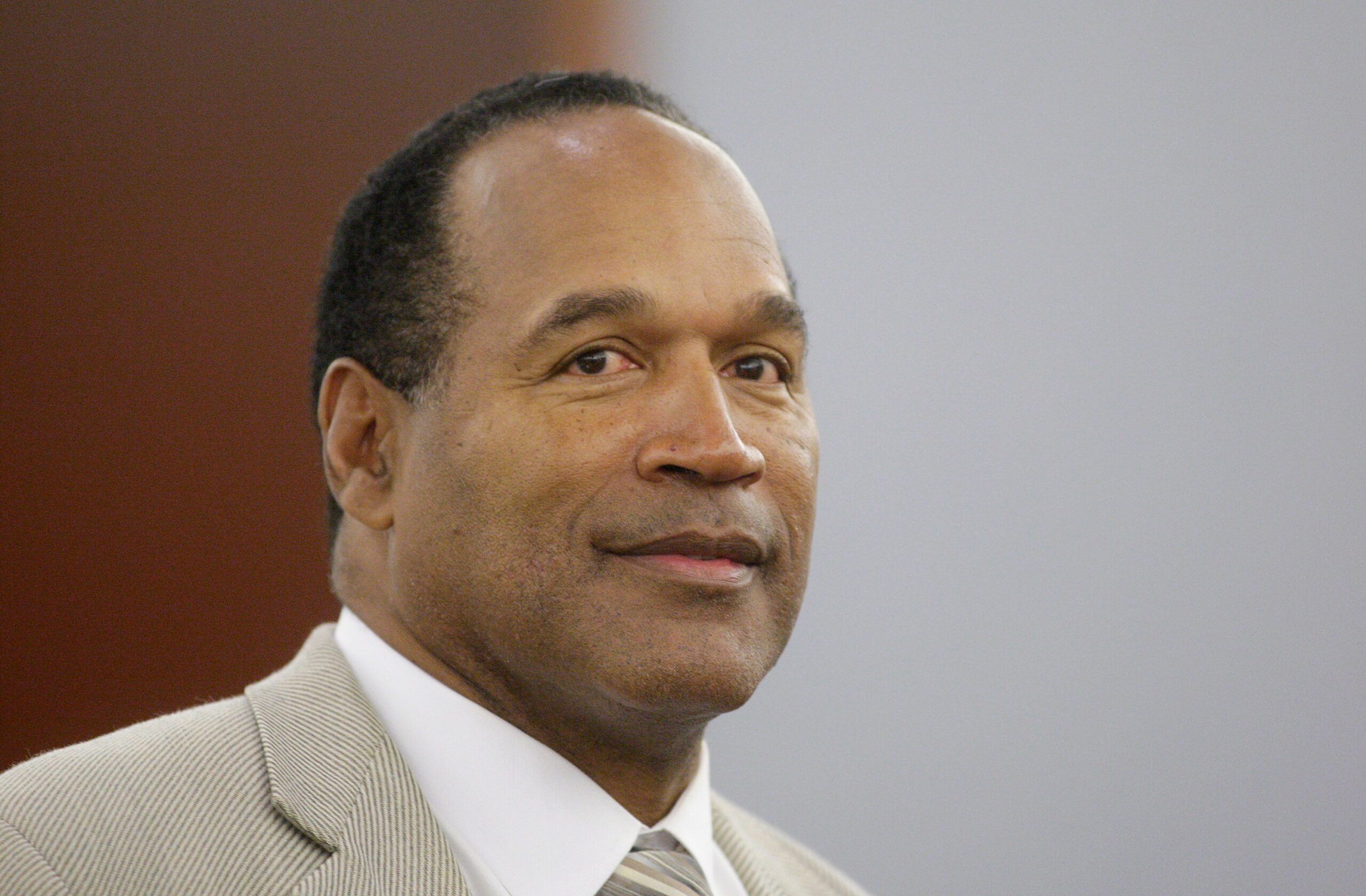 A man in a light suit and striped tie looks slightly to the side.