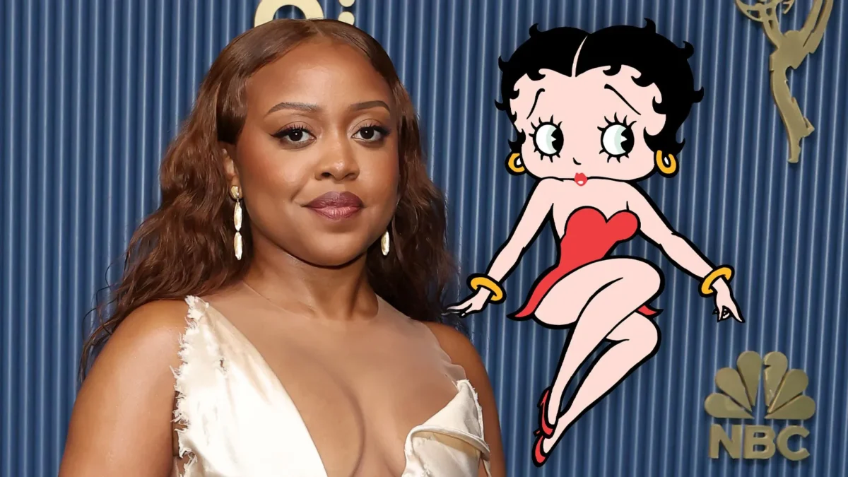 A woman in a white dress stands beside a cartoon character in a red dress against a blue curtain backdrop.