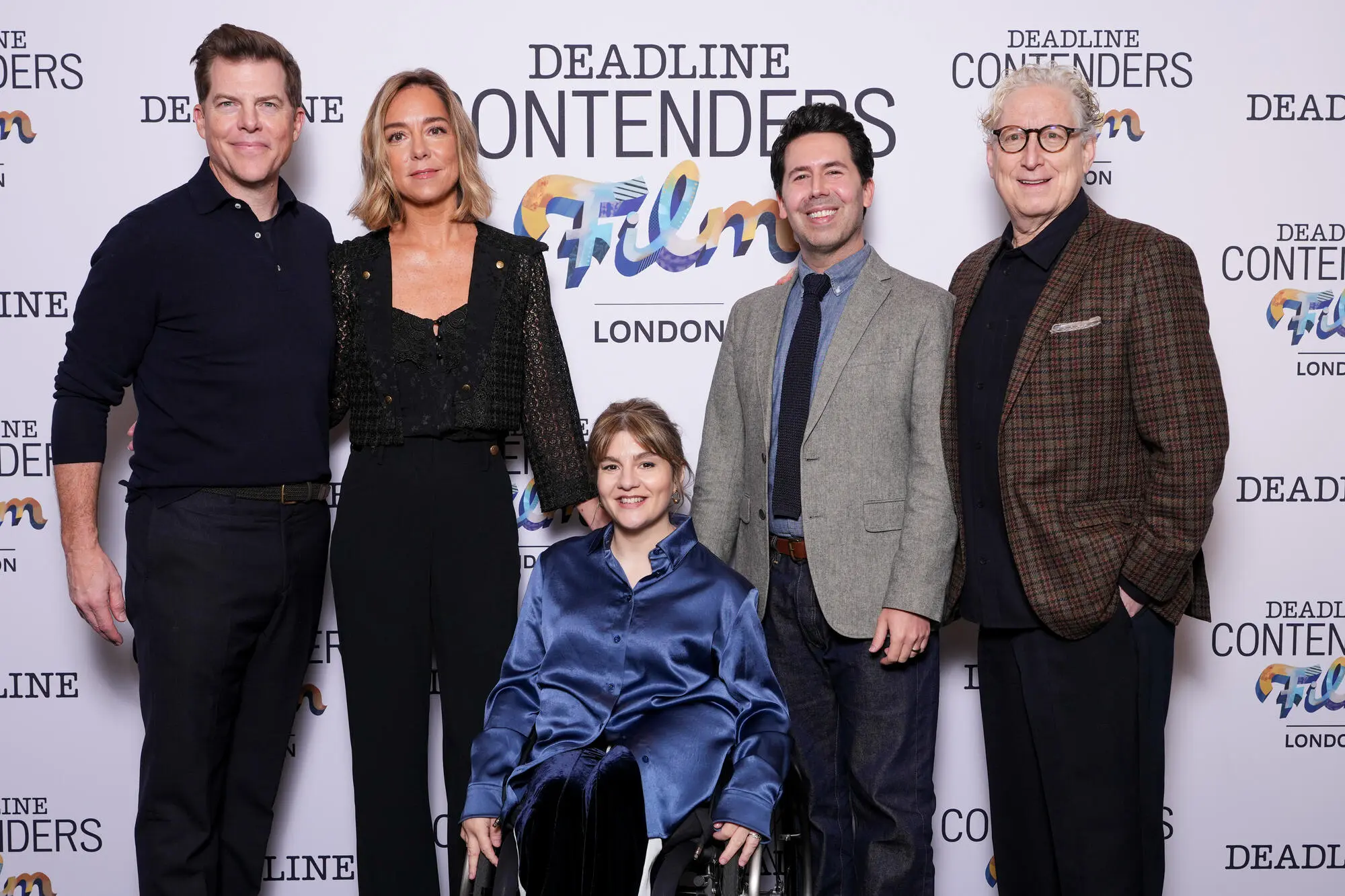 Five adults pose before a Deadline Contenders Film London backdrop, with one seated in a wheelchair.
