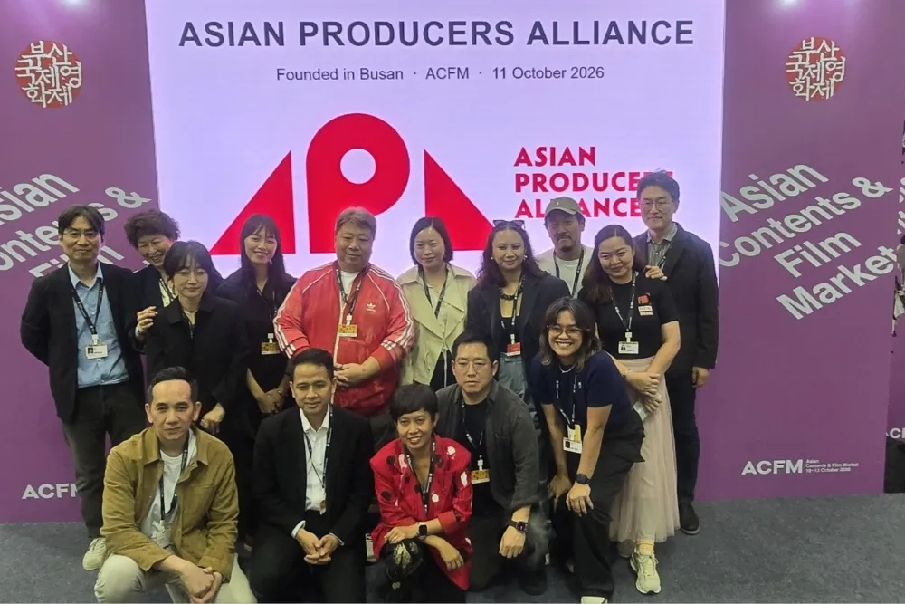 Group of people posing in front of an Asian Producers Alliance backdrop at an industry event.
