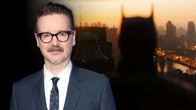 A bespectacled man in a suit stands before a blurred bat-eared silhouette and sunset city skyline.